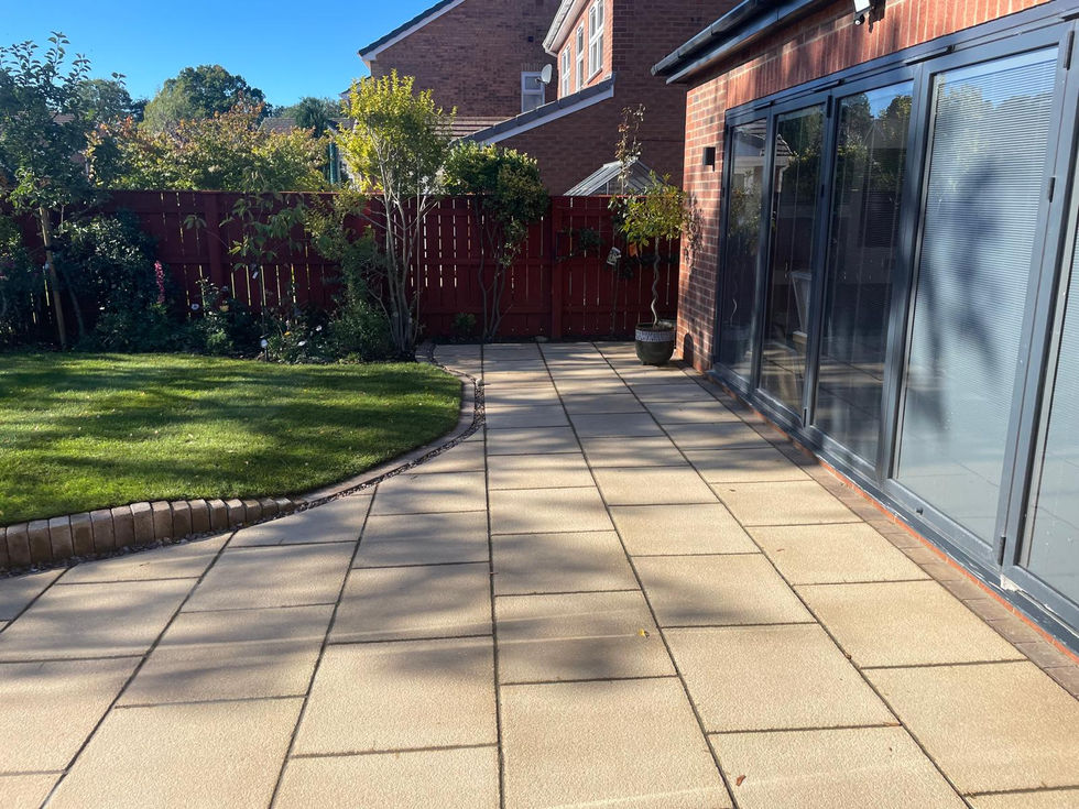 Garden patio with seating area and potted trees, adjoining new house extension.
