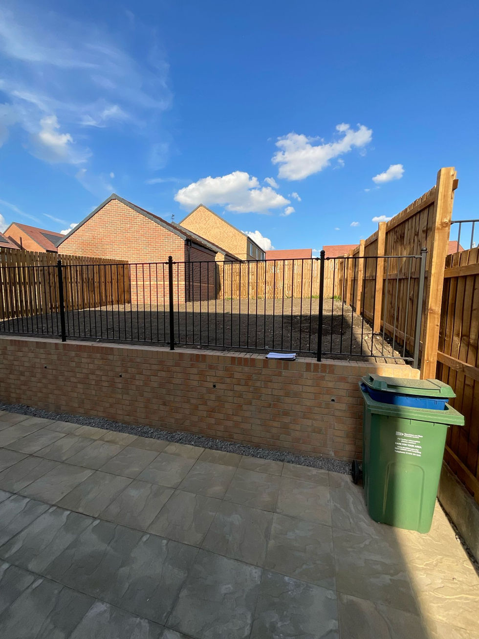 Porcelain patio area with raised retaining wall and metal safety railings.