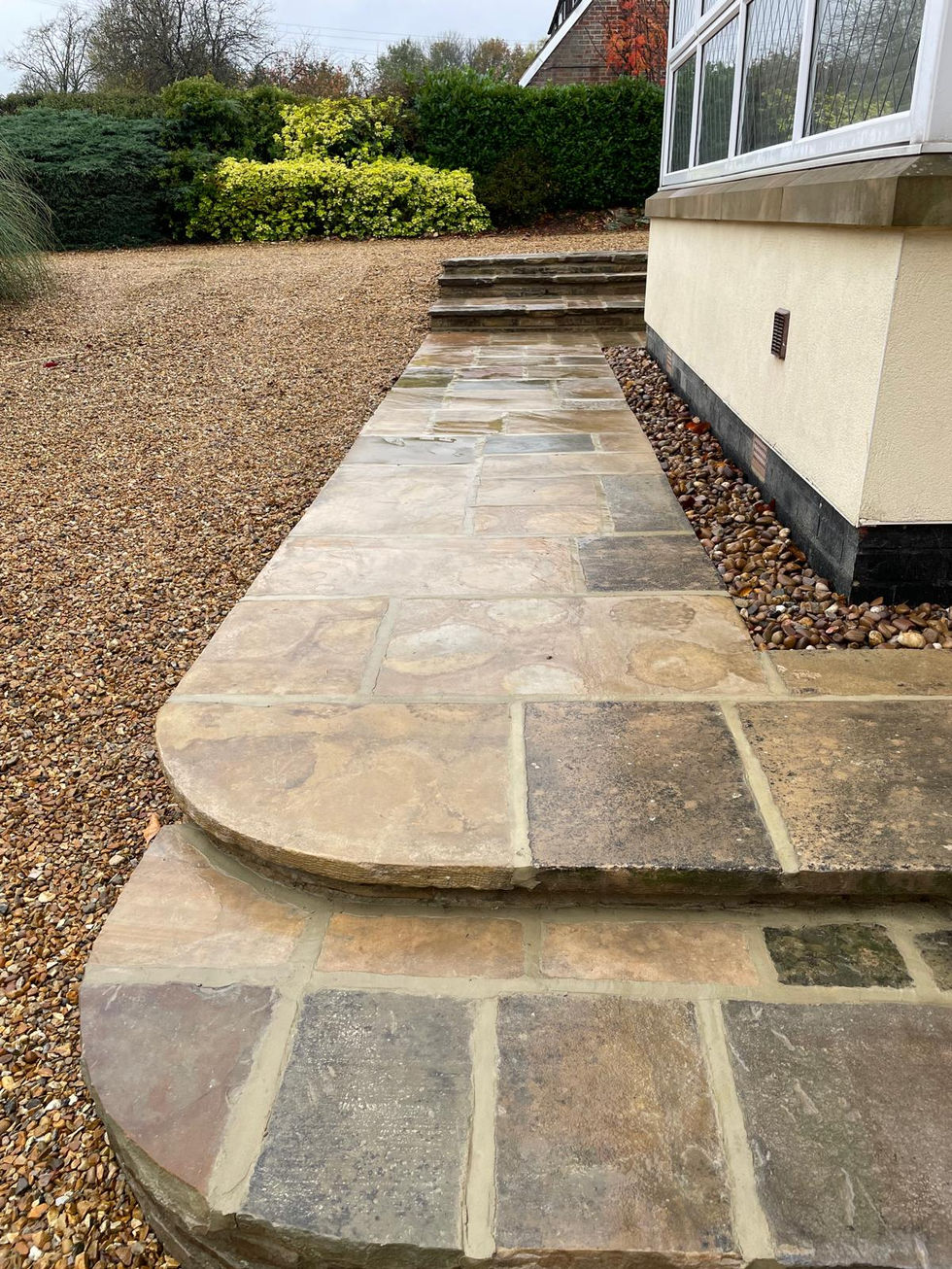 Restored York stone steps and pathway bordered by pea gravel, showing smooth, even joints and the warm natural tones of traditional stonework.