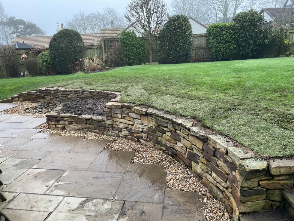 Natural stone retaining wall and lawn levels before alteration works
