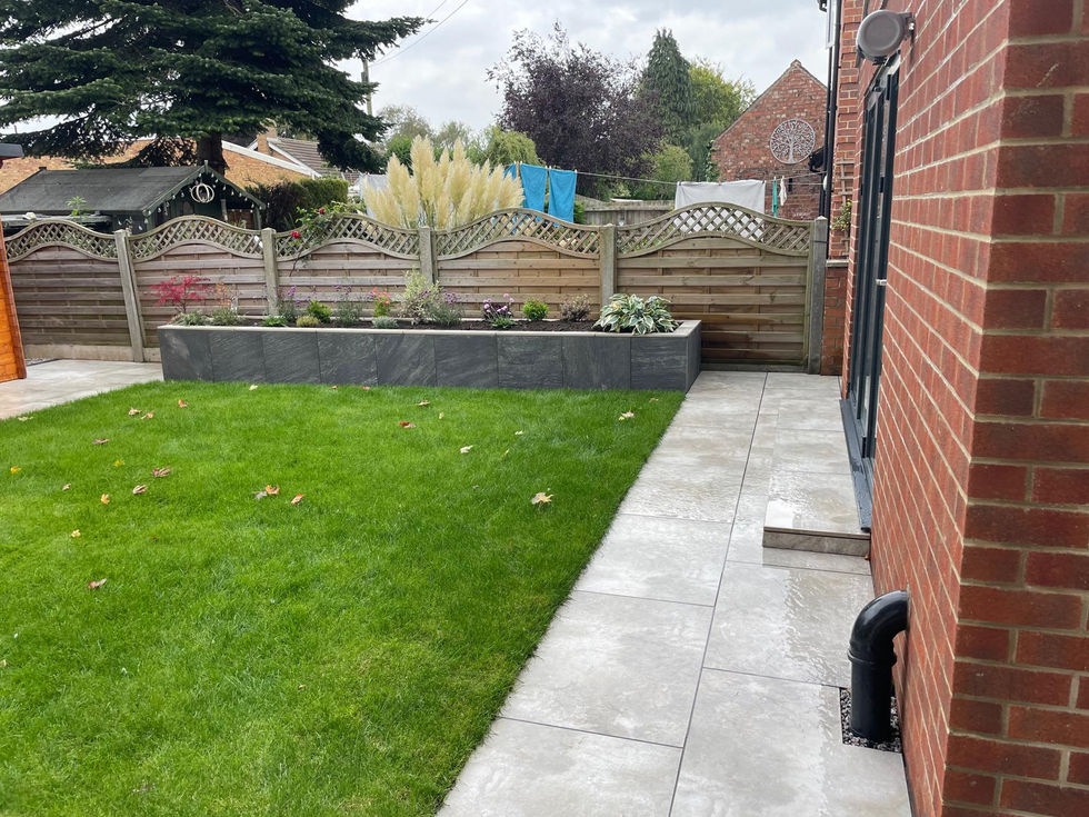 Modern raised planter with slate cladding, filled with lush hostas and seasonal plants.