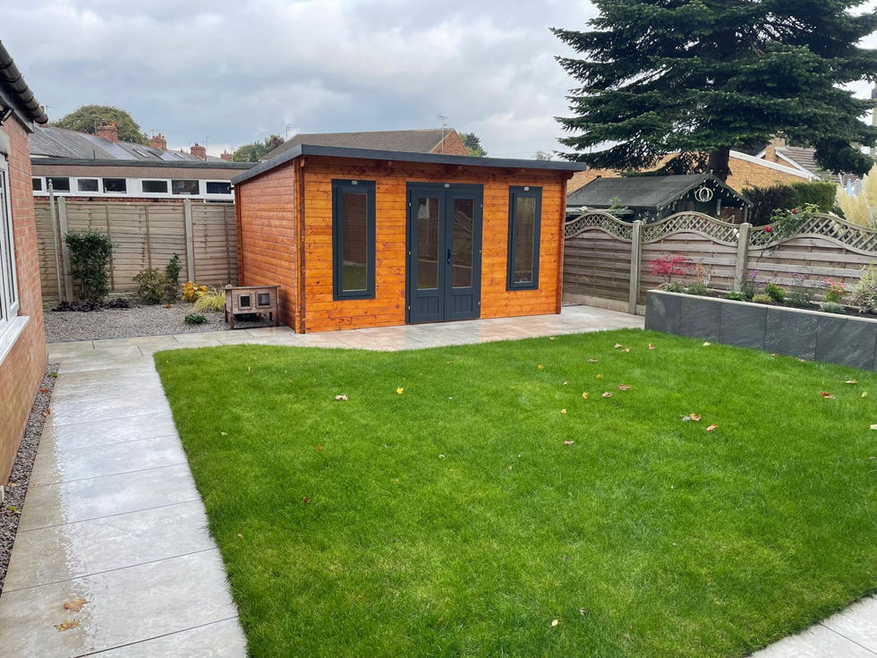 Timber-clad garden room with lawn, porcelain patio, and raised planting borders.