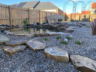 Landscaped garden with pond, stones, and wooden fence, Garden Design, Wilkinsons Landscapes.