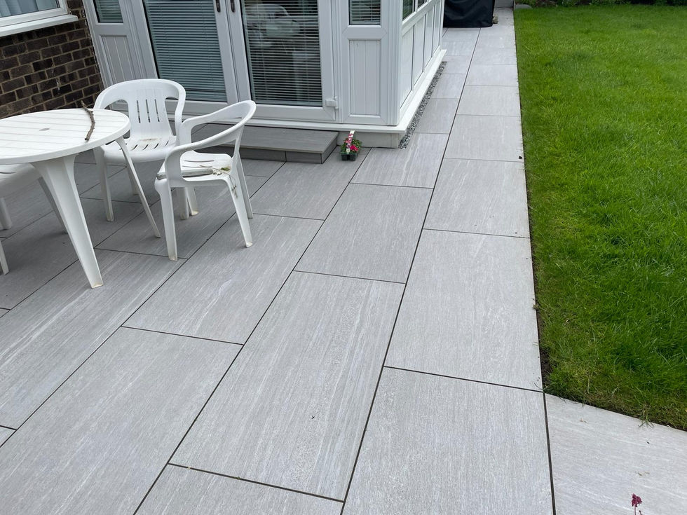 Large format light grey porcelain patio creating a clean contemporary outdoor seating space beside a conservatory.