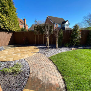 Circular porcelain patio with curved brick pathway and decorative gravel borders
