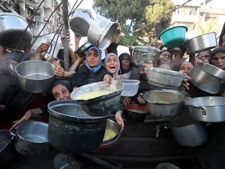 Palestinian women and children raising pots for food in Gaza, July 14 – Photo by Mahmoud Issa/Anadolu/Getty Images