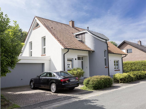 Einfamilienhaus mit MIG-ESP Exterior Beschichtung – strahlend weiße Fassade mit grauen Akzenten, langfristige Energieeinsparung und dauerhafte Farbtreue.