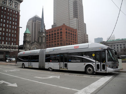 A cleveland BRT gray articulated bus driving down a street. RTA and Healthline are written on the side.