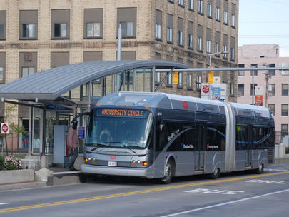 A gray articulated bus reading "university circle" waits at a bus station with a swooping roof.