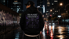 A person stands on a wet, graffiti-lined street at night, wearing a hoodie with a bold "Rare Frequency" design featuring a cool cat and speakers, illuminated by vibrant city lights.