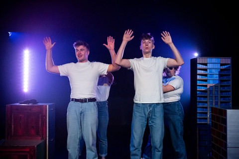 event photography of a play, two young men in white shirts and blue jeans are raising their hands in the air