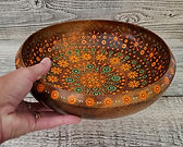 Bowl painted in shades of orange, russet, and sage green with hand to show scale