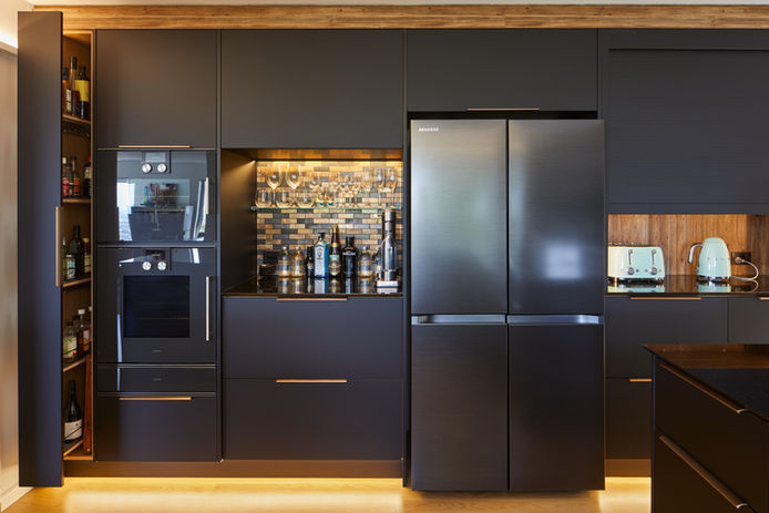 Luxurious kitchen renovation designed by an interior designer, featuring a striking black and gold colour scheme, custom cabinetry with clever storage solutions, and high-end finishes for a sophisticated look.