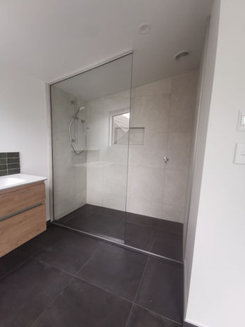 A modern and stylish bathroom featuring a walk in shower, a built in tiled shower niche and wall hung vanity.