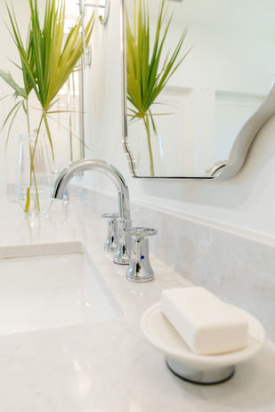 close up of faucet, mirror, and soap on countertop in bathroom