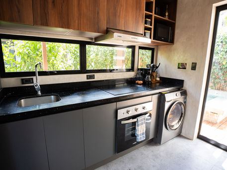 A modern, minimalist kitchen with a clean and functional layout. The combination of warm wood, matte gray fronts, and a black countertop provides an elegant and timeless finish, optimizing light, organization, and everyday use.
