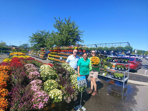 Simply Set Merchandisers in a group photo with their displayed flowers in the background