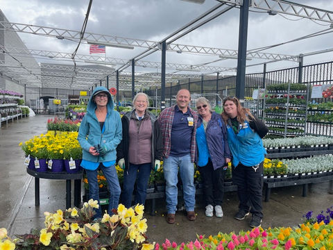 Simply Set Merchandisers in a group photo with their displayed flowers in the background