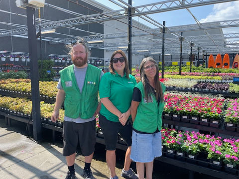 Simply Set Merchandisers in a group photo with their displayed flowers in the background