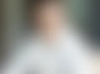 Felix Fröhlich, Versicherungsmakler aus Potsdam, sitzt lächelnd am Schreibtisch mit Laptop und Brille im weißen Hemd.