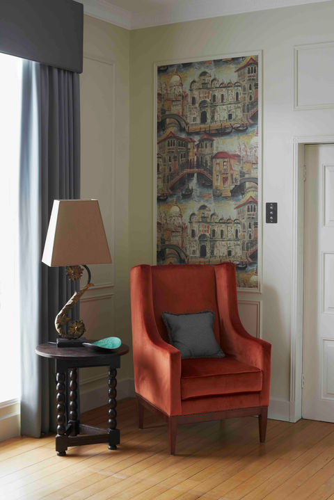Living room corner with burnt orange armchair and side table.