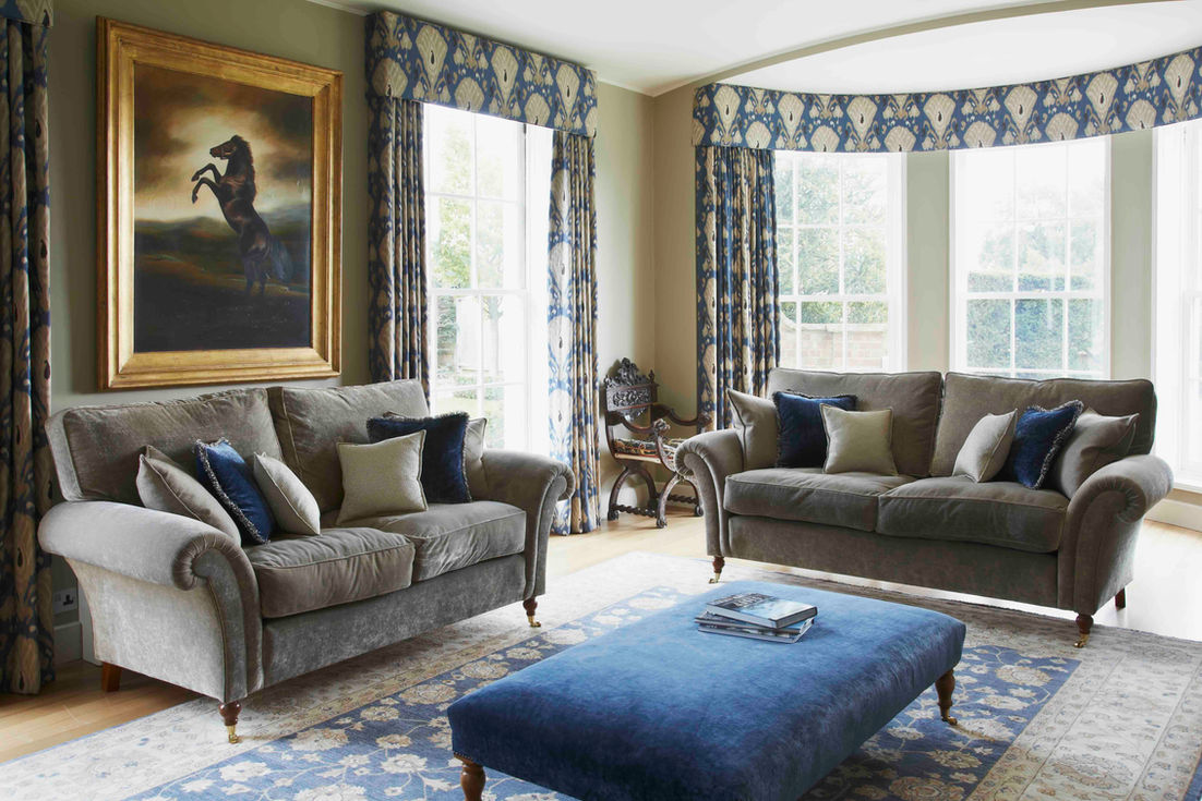 Elegant country manor living room with blue patterned curtains, grey sofas and statement artwork.