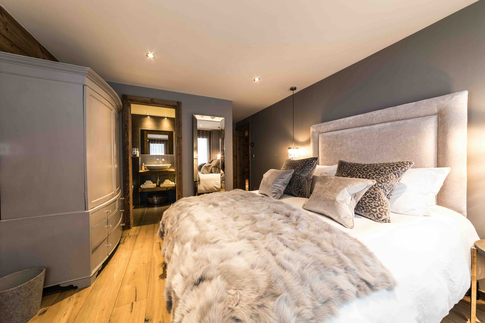 Luxury chalet guest suite with statement mirrored wardrobes and fur layered accents.