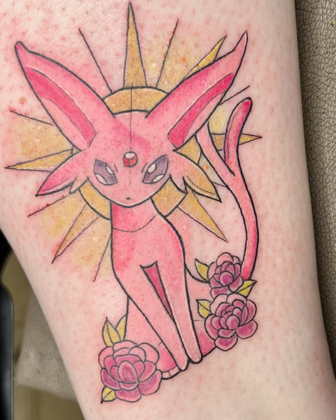 Buntes Anime-Tattoo des Pokémons Psiana (Espeon) in kräftigem Rosa vor einer goldenen Sonne und umrahmt von dunklen Rosen, gestochen bei Neuanstich in Horneburg Landkreis Stade..
