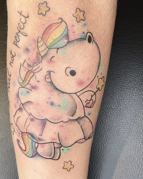 Süßes Comic-Einhorn-Tattoo mit bunten Aquarell-Farbeffekten, kleinen Sternen und einem Schriftzug an der Seite, gestochen im Tattoo-Studio Neuanstich in Horneburg Landkreis Stade..