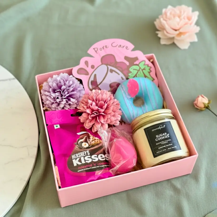 Aesthetic pink gift hamper for women featuring a sugar cookie scented candle, donut bath bomb, and Hershey’s chocolate. Ideal birthday gift box, self-care package, or bridesmaid proposal gift. Styled in a soft girl aesthetic on a lace background.