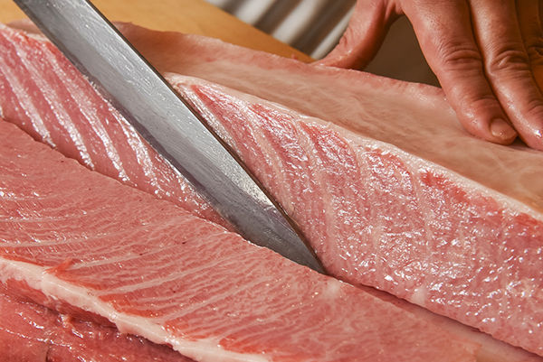 Chef expertly preparing fresh tuna with traditional Japanese culinary precision