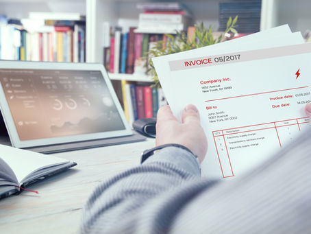 Invoice in hands of a user with a Laptop in the background