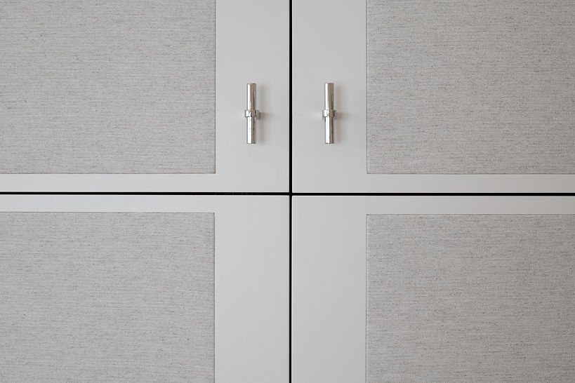 Close-up of the upholstered custom closet doors with polished nickel T-pulls.