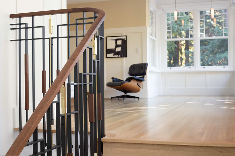 The enclosed front porch features expansive multi-lite windows, Craftsman paneling and a custom steel, walnut and brass stair guardrail.