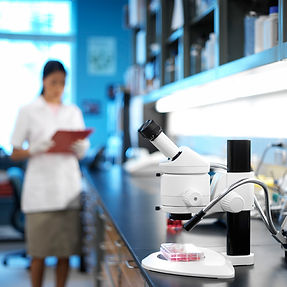 Scientist in lab coat with microscope and other equipment, Labmetrics