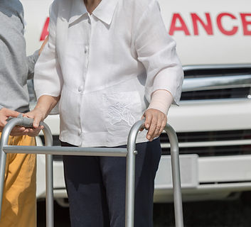 Elderly person with walker and caregiver near ambulance