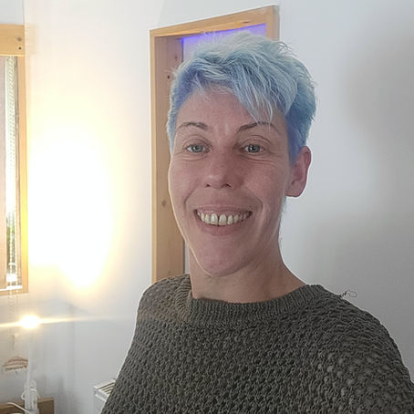 Woman smiling warmly in a softly lit therapy room at Sunshine Holistic Therapy, Levenshulme