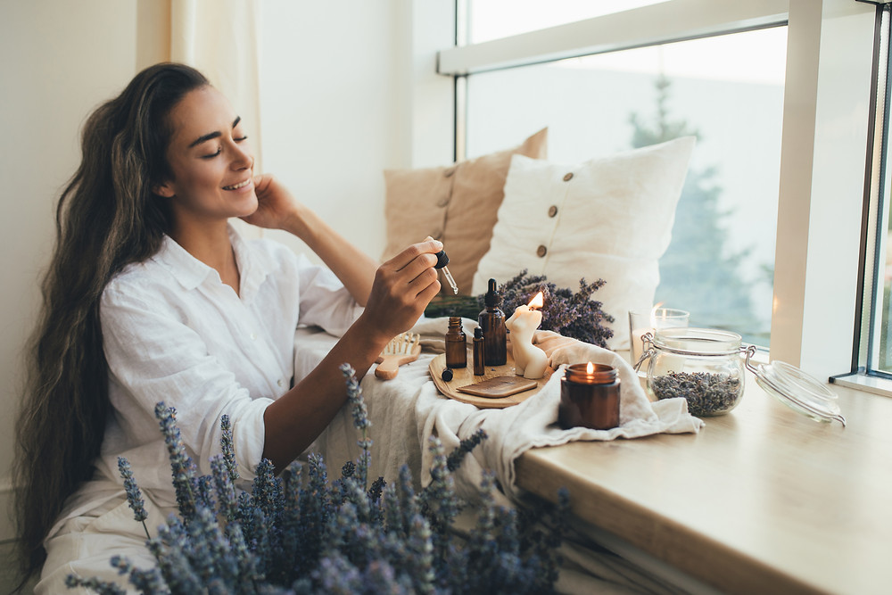 Happy woman with essential oils, candle burning, lavender
