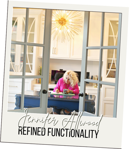 Jennifer Allwood seated at a blue desk, writing in a thoughtfully designed workspace with refined, functional details