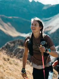 Cat Bradley navigates a challenging mountain trail during an ultramarathon, using trekking poles while focused on the terrain ahead, highlighting the determination required for long-distance endurance racing.