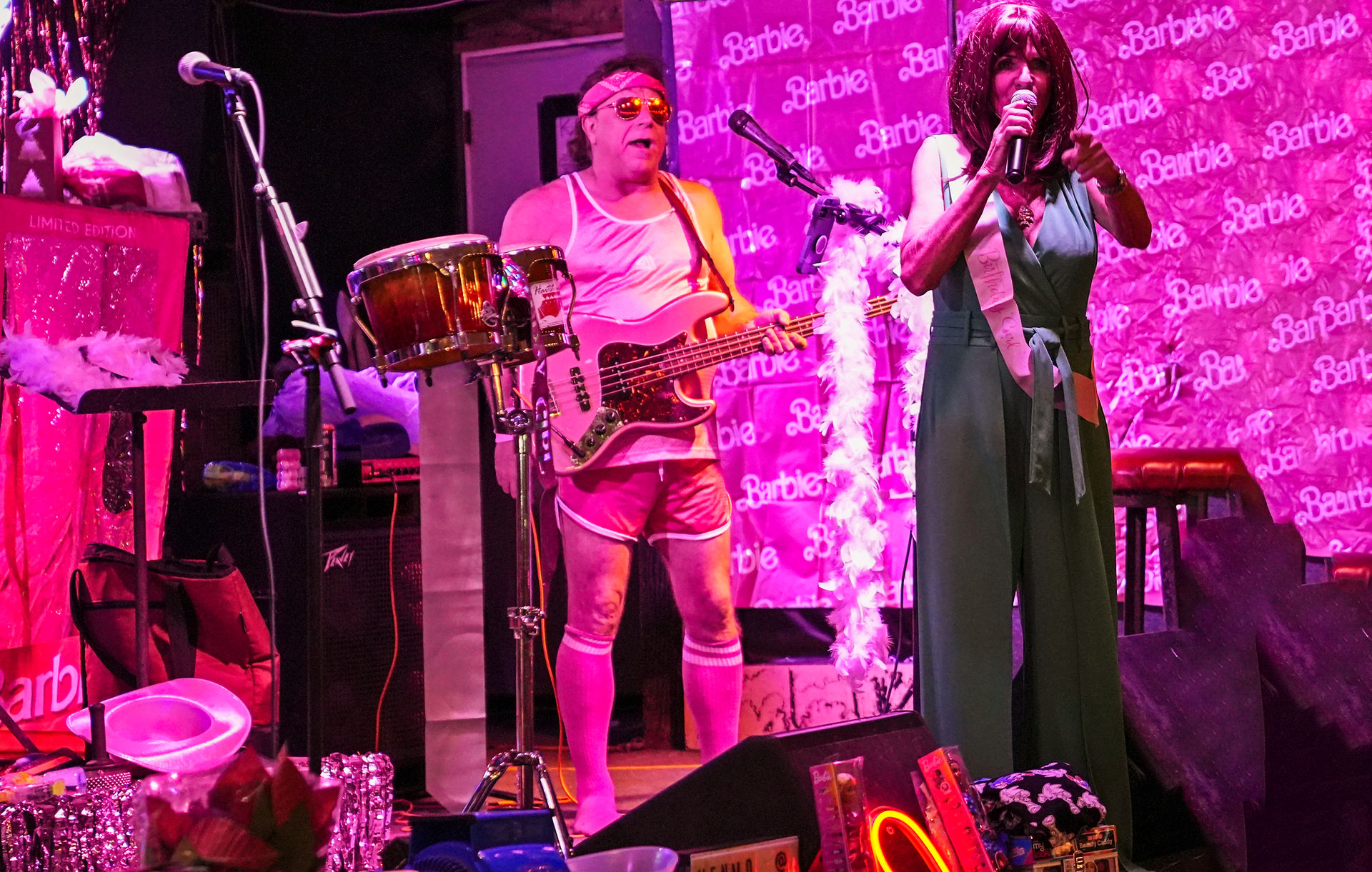 Rhonda Hart performing on stage alongside band members at a lively Barbie-themed fundraiser at the Flora-Bama.