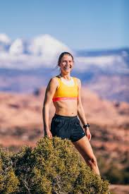 Cat Bradley smiles while holding her dog during a trail-running adventure in the desert, offering a glimpse into the personal side of her life beyond competition.