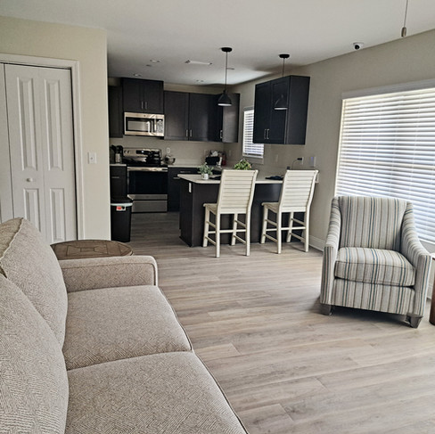 Comfortable living room inside Anchorage Children's Home's Transitional Living Program featuring coastal-inspired furnishings, a seating area, and an open-concept kitchen designed to provide youth with a safe and welcoming environment.