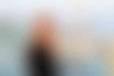 Professional portrait of a Lauren Chapman  standing near a marina with sailboats softly blurred in the background.