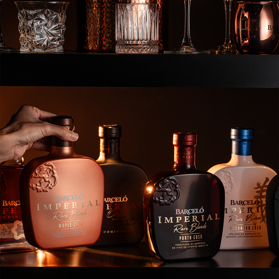 Bottles of Barcelo Imperial range on shelf with hand picking one up