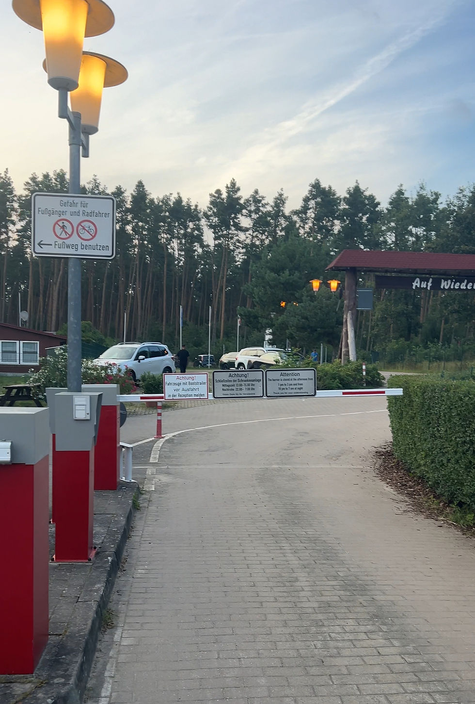 Campingplatz-Zufahrt mit Schrankenanlage und Hinweisschildern – perfekter Stellplatz für Wohnmobile, umgeben von Natur und Bäumen. Tipps und Erfahrungen zur Stellplatzwahl für große Fahrzeuge wie 12-Meter-Wohnmobile.