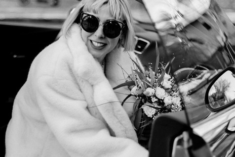 karolinako Winter Wedding in Berlin Friedrichshain Fashionable modern winter bride wearing white fur and sunglasses getting out of the car. 