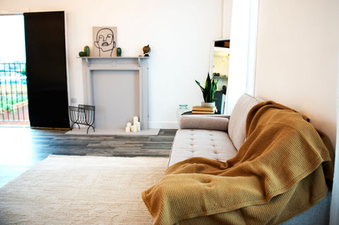 Grey sofa with yellow blanket across