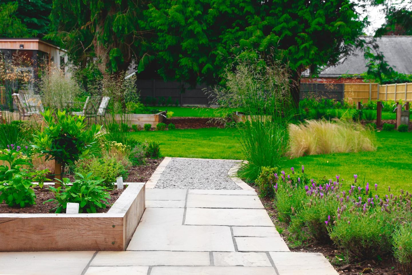 Garden path leading to fresh lawn past flower beds