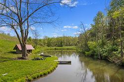 Fishing Pond at French Broad River Farms. The grass is bright green and the trees are reflecting int